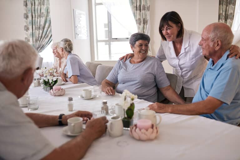 smiling seniors talking over tea with their retirement home nurse
