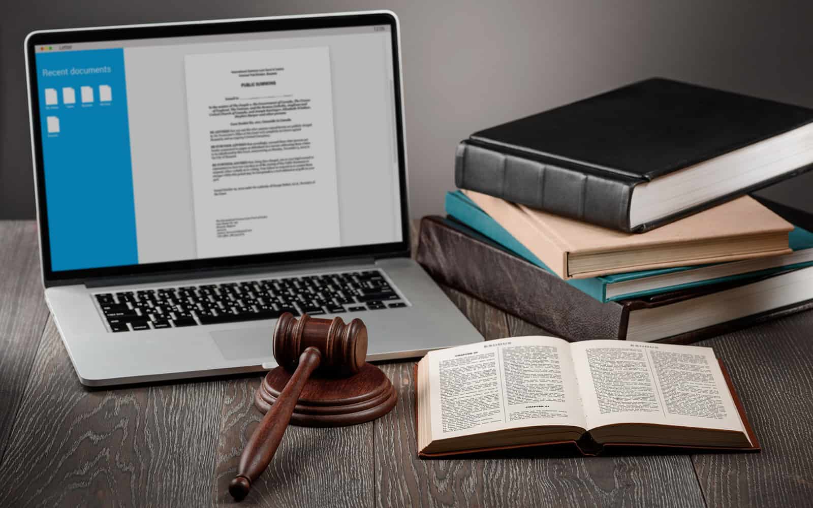 laptop, gavel, bible and pile of books on a judge's desk